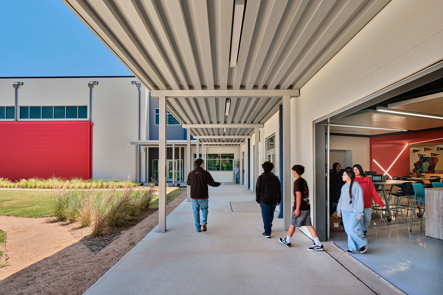 Students exit the makerspace through the open overhead door to enter the courtyard.